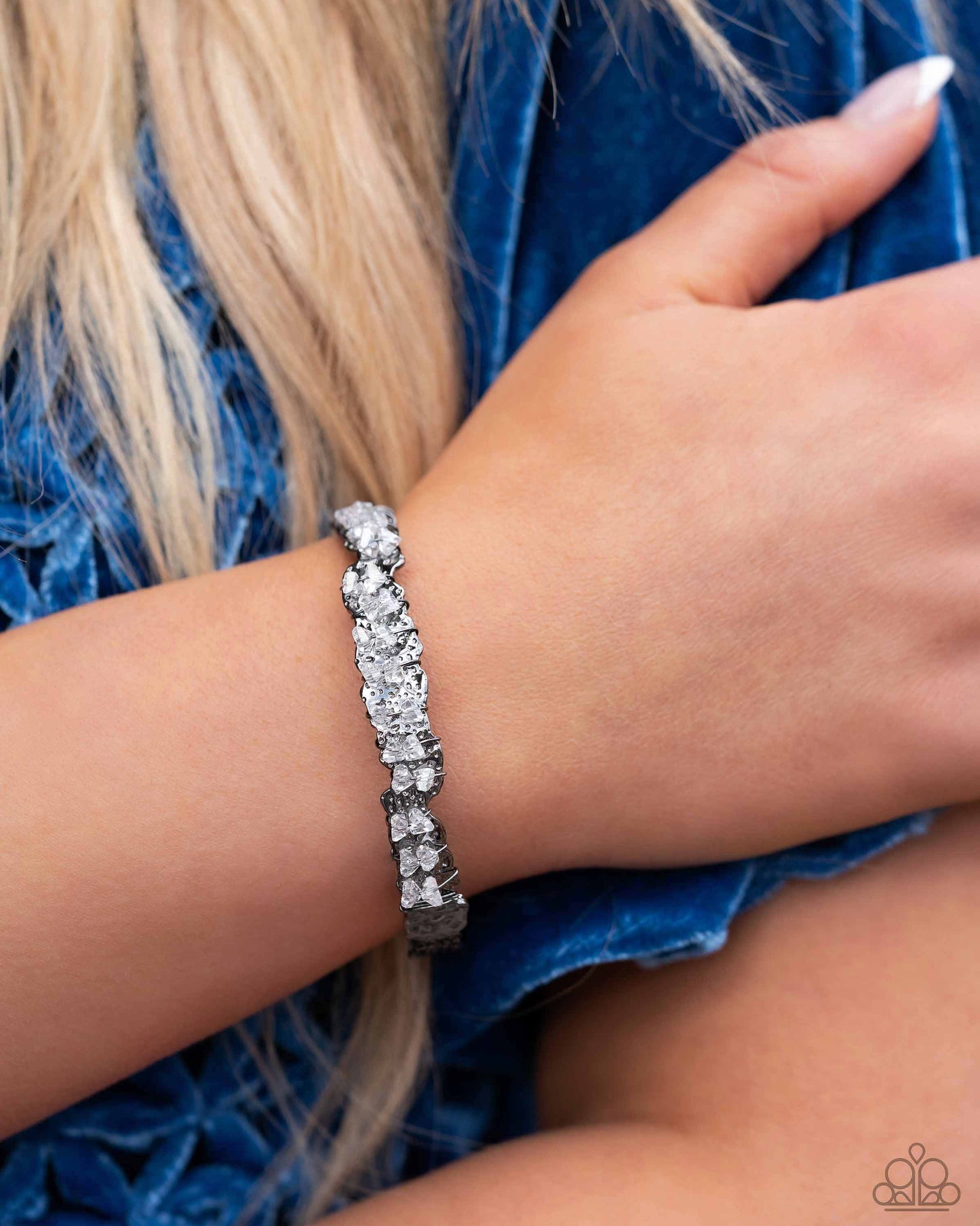Paparazzi Accessories Enticingly Icy - Black Featuring raw cuts, pairs of icy white gems are fitted in place across the center of a hammered and asymmetrical gunmetal cuff with dainty gunmetal wires. Reminiscent of ice, the sharp rhinestone accents are ha