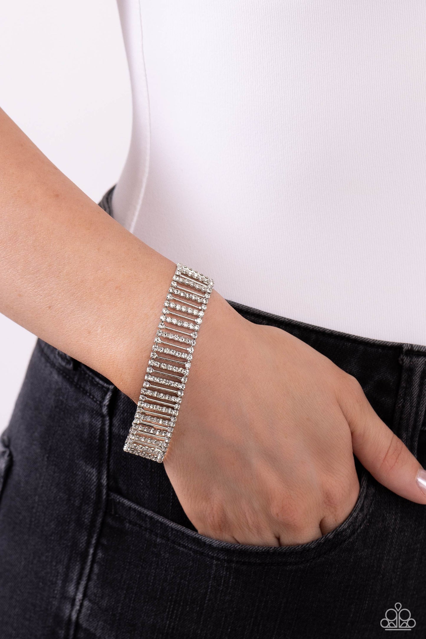 Paparazzi Accessories Elusive Elegance - White Separated by white rhinestones, rhinestone-covered silver bars and thin sleek silver bars alternate around the wrist for a glitzy display. Features an adjustable clasp closure. Sold as one individual bracelet