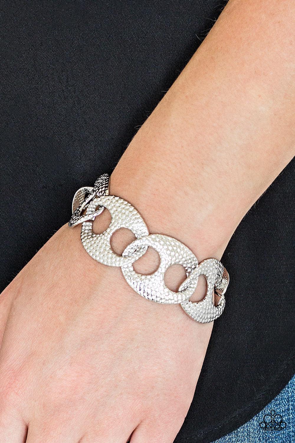 Paparazzi Accessories Casual Connoisseur - Silver Embossed in shimmery circular patterns, asymmetrical silver frames link across the wrist for a casually industrial look. Features an adjustable clasp closure. Jewelry
