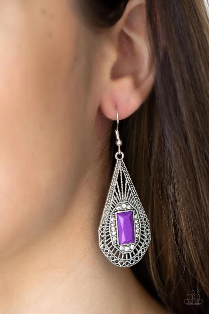 Paparazzi Accessories Deco Dreaming - Purple A bright purple baguette-cut bead, bordered with sparkling white rhinestones, sits center stage inside a teardrop frame. Delicate art deco filigree fills the frame creating a richly embellished lure. Earring at