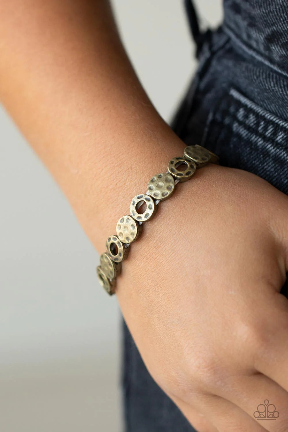 Paparazzi Accessories Metro Metalsmith - Brass A rustically hammered collection of brass rings and discs are threaded along stretchy bands around the wrist, creating a dainty metallic centerpiece. Sold as one individual bracelet. Jewelry