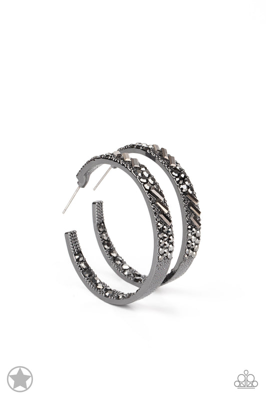 Paparazzi Accessories GLITZY By Association - Black The front facing surface of a chunky gunmetal hoop is dipped in brilliantly sparkling hematite rhinestones while light-catching texture wraps around the back. The interior of the hoop features the opposi