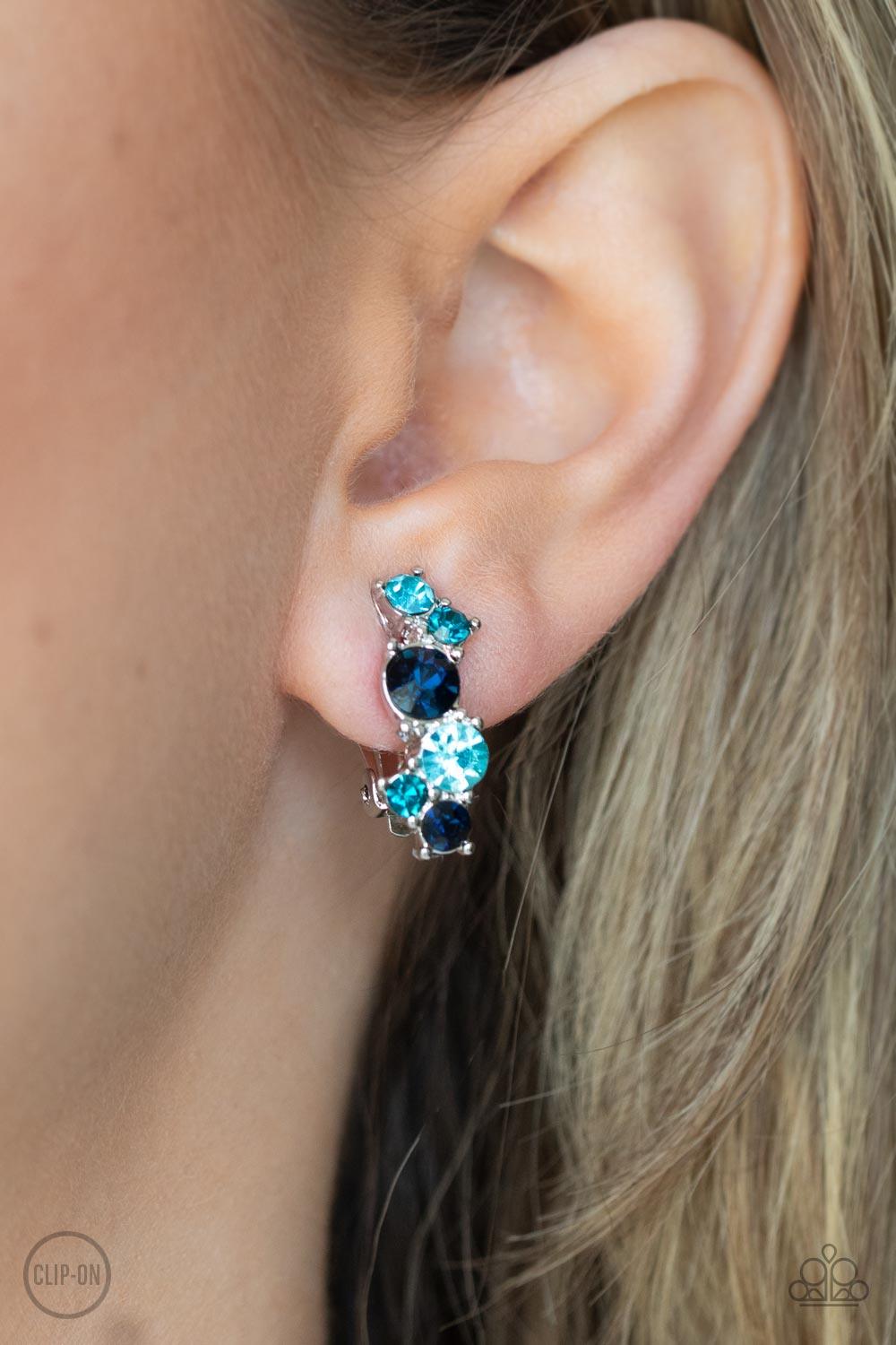 Paparazzi Accessories Cosmic Celebration - Blue Varying in shades of blue, mismatched rhinestones delicately coalesce into a dainty frame for a colorfully sparkly display. Earring attaches to a standard clip-on fitting. Sold as one pair of clip-on earring