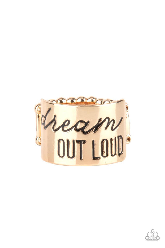 Paparazzi Accessories Dream Louder - Gold The front of a thick gold band is stamped in the phrase, "Dream out loud," creating an inspirational centerpiece across the finger. Features a stretchy band for a flexible fit. Sold as one individual ring. Jewelry