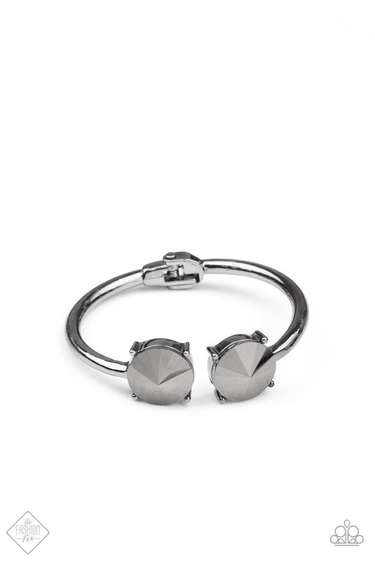 Paparazzi Accessories Spark and Sizzle - Black Two dramatically oversized hematite rhinestones are nestled inside pronged gunmetal fittings at the ends of a hinged gunmetal cuff, creating a smoldering statement piece that wraps boldly around the wrist. Fe
