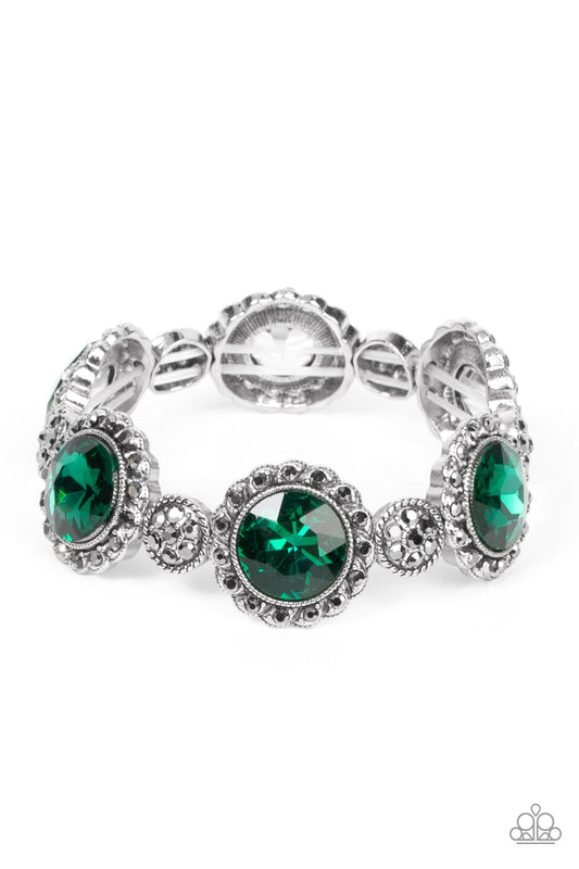 Paparazzi Accessories Palace Property - Green An oversized green rhinestone adorns the center of a hematite rhinestone petaled floral frame. Infused with hematite dotted silver accents, the glitzy floral frames sparkle along stretchy bands around the wris