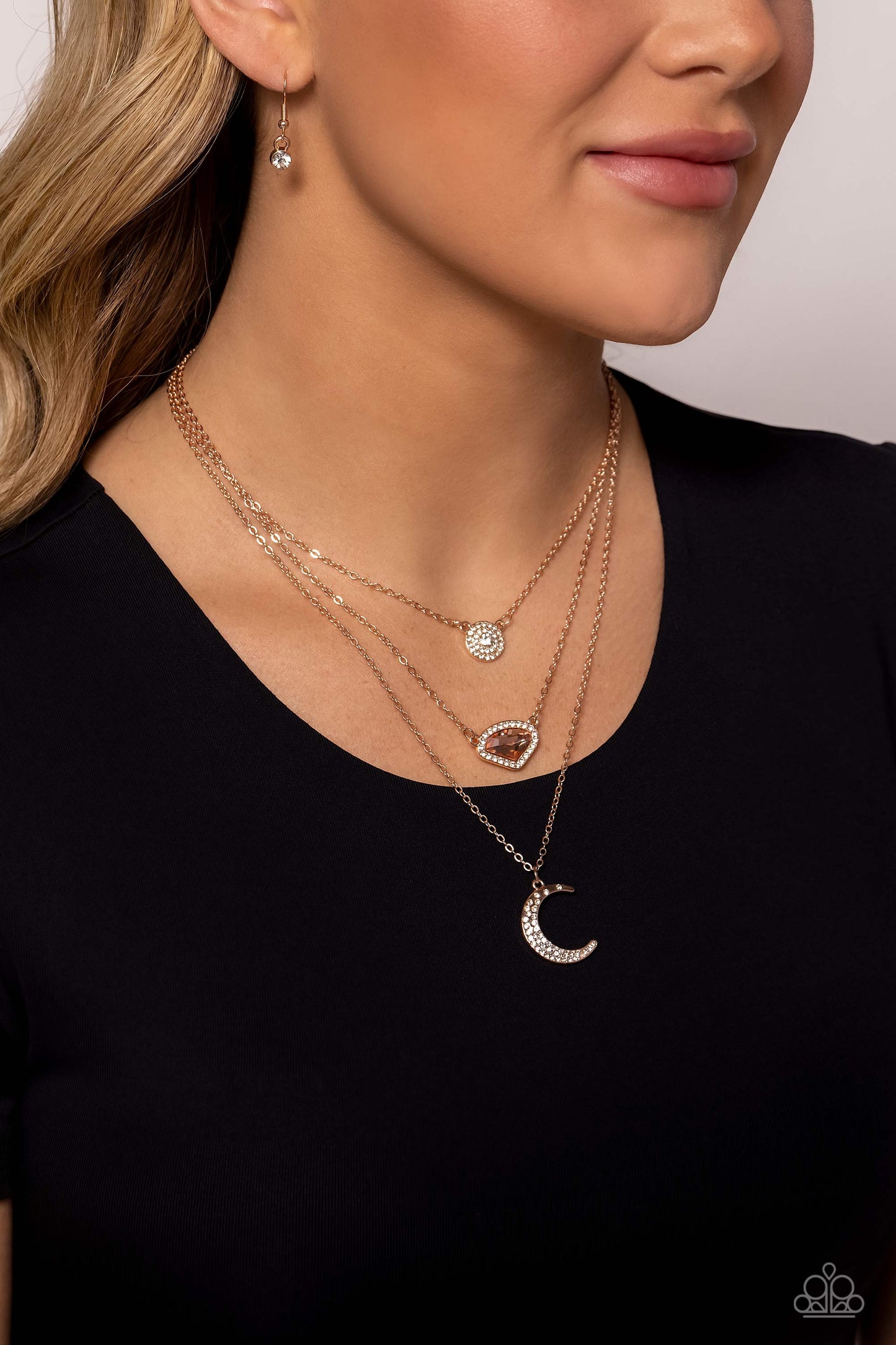 Paparazzi Accessories Lunar Lineup - Rose Gold Three shimmery rose gold chains, infused with three stellar pendants, layer across the chest in a celestial display. A dainty, white rhinestone-encrusted, rose gold pendant with a white center swings from the