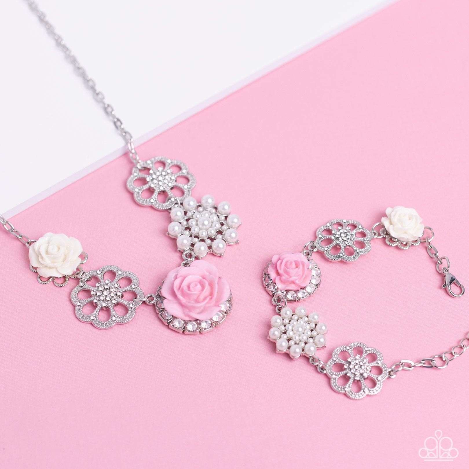 Paparazzi Accessories Tea Party Theme - Pink A collection of whimsical, refined flowers gathers along a flat, sleek silver link chain. The featured charms include an ivory resin rose blooming atop a glittery silver floral silhouette, two silver flowers du