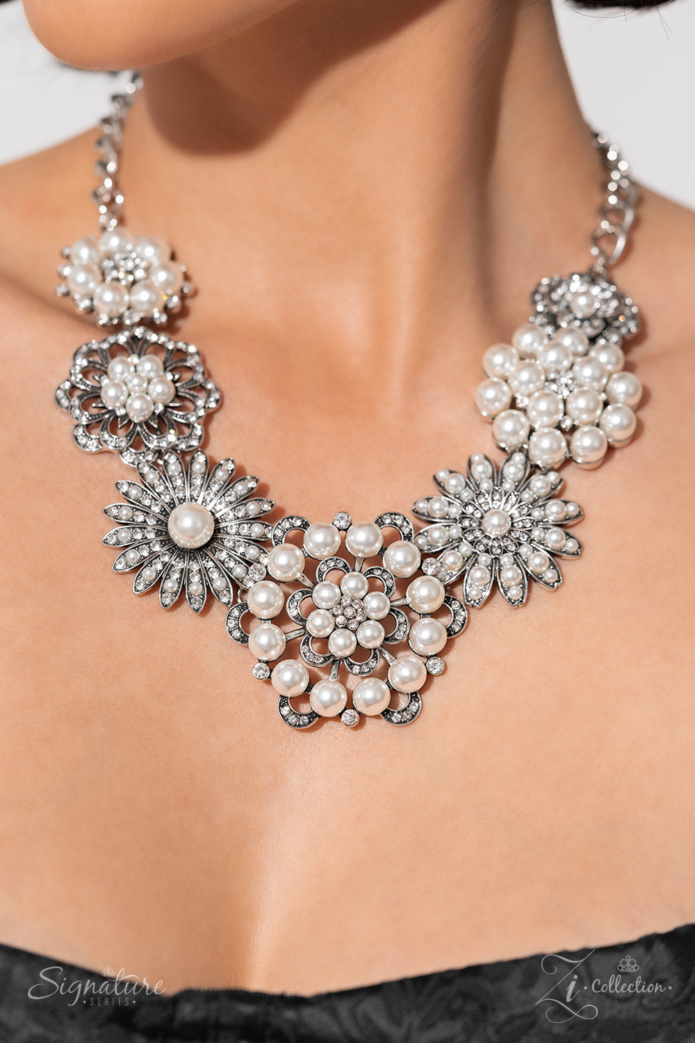 Paparazzi Accessories The Raven Polished white pearls and brilliant white rhinestones bloom atop a framework of silver, forming seven unique flowers adorned in dizzying detail. Each flower features a unique centerpiece encircled by silver petals lined wit
