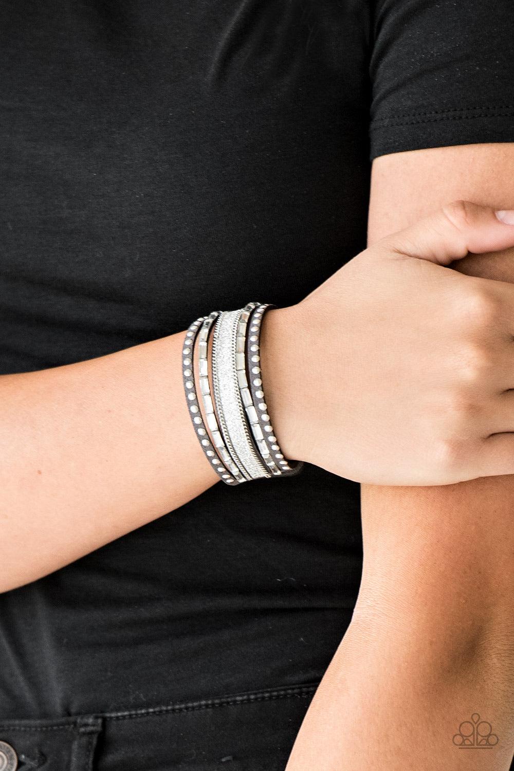 Paparazzi Accessories Seize The Sass - Silver Shimmery silver studs, dainty silver chains, and white emerald style cut rhinestones are encrusted along a gray suede band dusted in a sparkling center for a sassy look. Features an adjustable snap closure. So