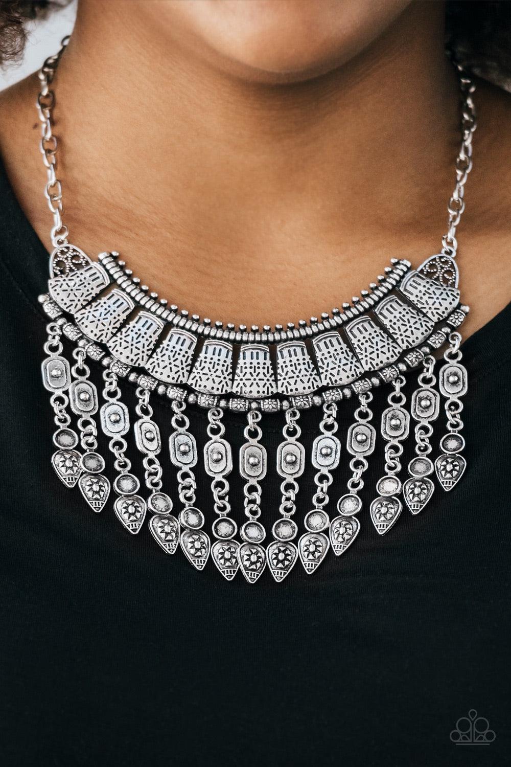 Paparazzi Accessories The Desert is Calling - Silver Stenciled in tribal inspired details, shimmery silver plates connect below the collar, coalescing into a crescent pendant. Embossed and studded in ornate patterns, antiqued silver beads swing from the b