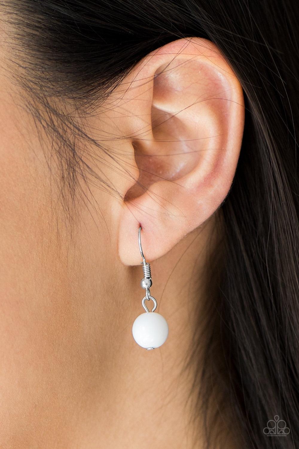 Paparazzi Accessories Carefree And Capricious - White Polished white and faceted silver beads trickle along shimmery silver hoops for an asymmetrical look. The colorful beading gives way to layers of shimmery silver chain for a seasonal finish. Features a