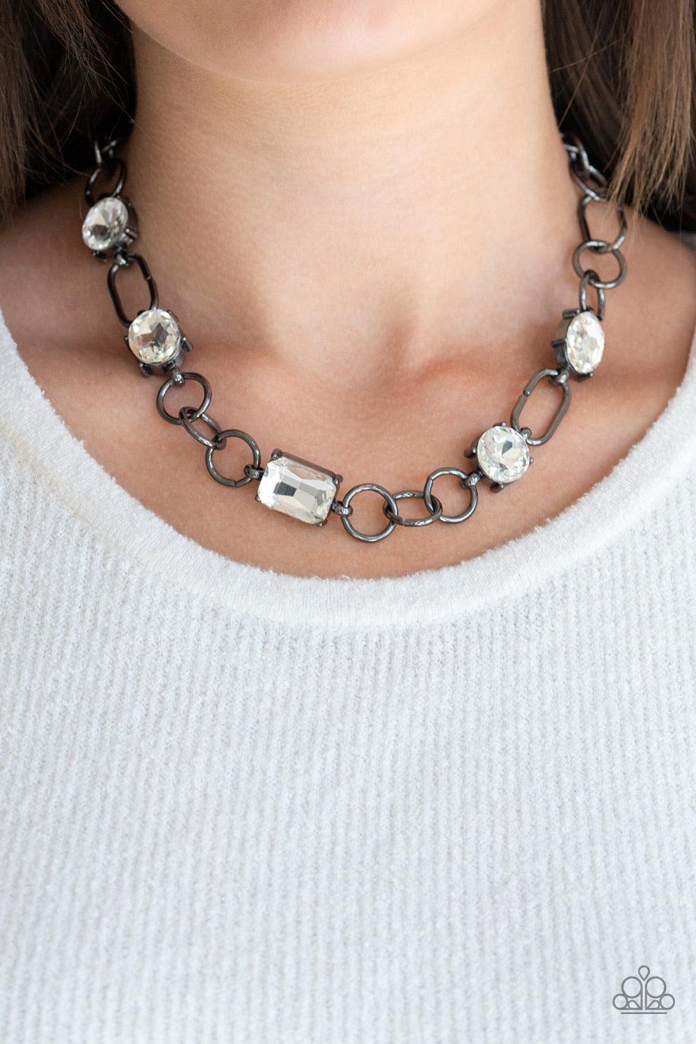 Paparazzi Accessories Urban District - Black Featuring round, oval, and emerald style cuts, glittery white rhinestone fittings link with mismatched gunmetal rings below the collar for an edgy glamorous look. Features an adjustable clasp closure. Necklaces