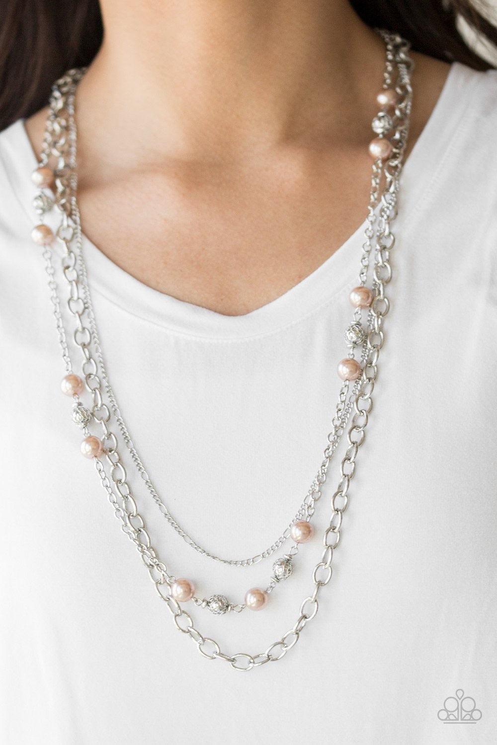 Paparazzi Accessories Classical Cadence - Brown Wrapped in wire mesh, classic silver beads join pearly brown beads along a shimmery silver chain. Varying in size and shimmer, mismatched silver chains layer behind the beaded strand for a refined finish. Fe