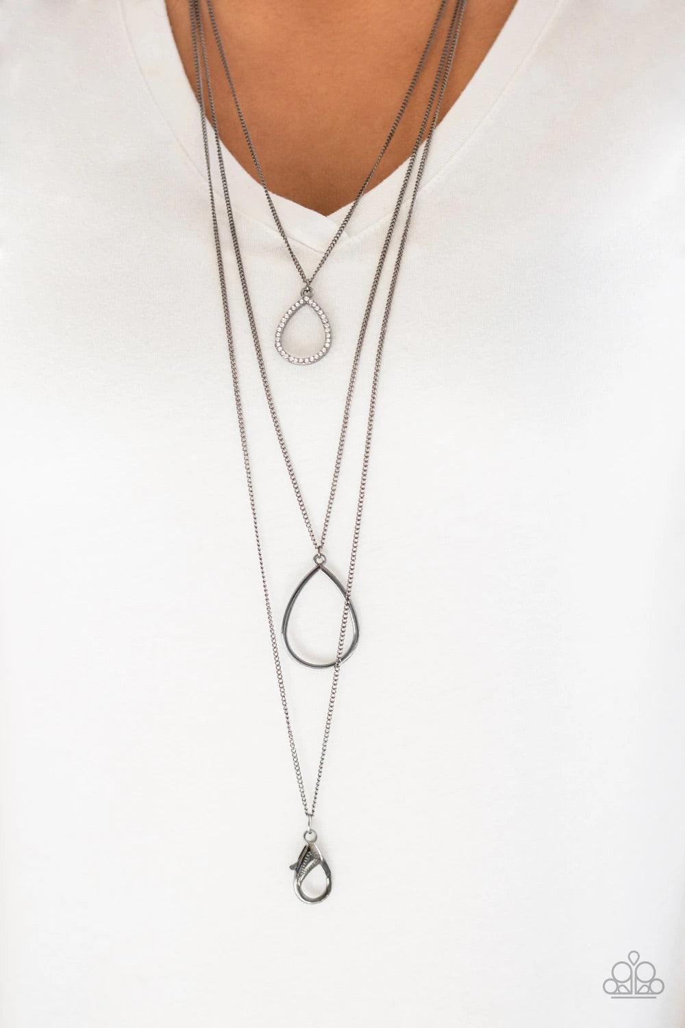 Paparazzi Accessories Make The World Sparkle - Black *Lanyard A white rhinestone encrusted teardrop gives way to a smooth gunmetal teardrop, creating refined layers down the chest. A lobster clasp hangs from the bottom of the design to allow a name badge