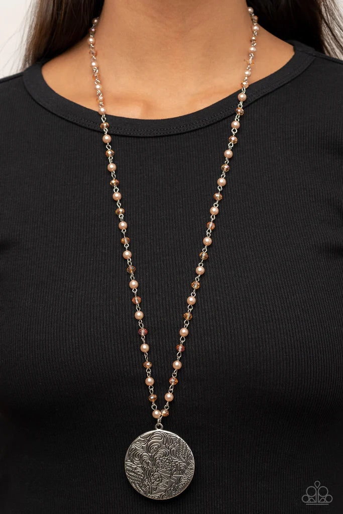 Paparazzi Accessories Secret Cottage - Brown An oversized silver disc stamped in a whimsical floral motif swings from the bottom of a pearly and crystal-like brown beaded chain, resulting in a romantic cottagecore inspired pendant. Features an adjustable