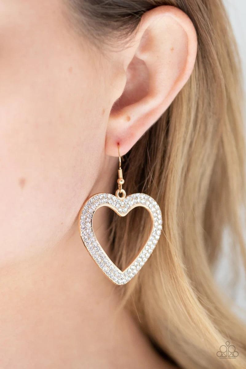 Paparazzi Accessories GLISTEN To Your Heart - Gold Two rows of glassy white rhinestones are encrusted along the front of a gold heart frame, creating a flirty centerpiece. Earring attaches to a standard fishhook fitting. Sold as one pair of earrings. Jewe