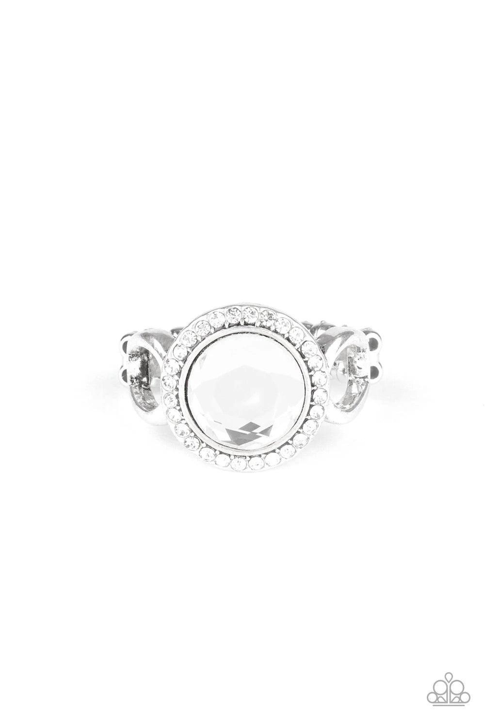 Paparazzi Accessories It’s Gonna GLOW! - White An oversized white gem is pressed into the center of a round silver frame encrusted in a ring of radiant white rhinestones for a regal flair. Features a dainty stretchy band for a flexible fit. Sold as one in