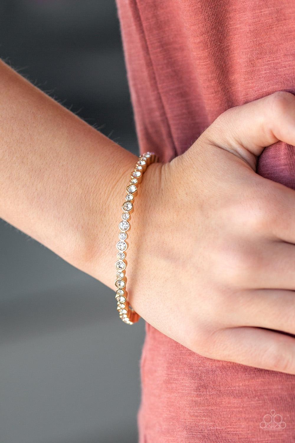 Paparazzi Accessories Seven Figure Fabulous - Gold A glistening gold bangle is encrusted in countless white rhinestones for a timeless look. Jewelry