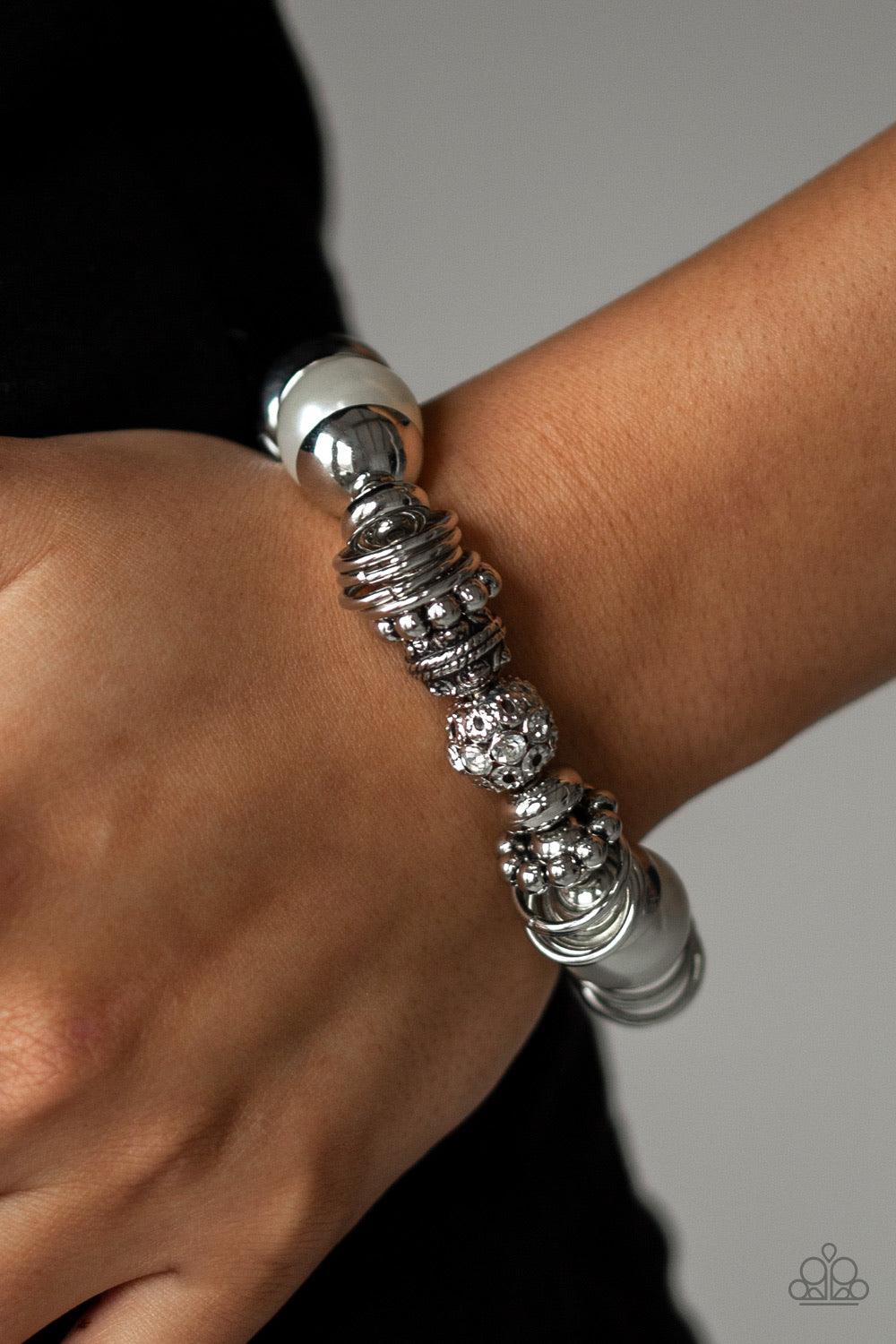 Paparazzi Accessories Uptown Tease - White A collection of oversized white pearls, mismatched silver accents, and white rhinestone encrusted beads are threaded along a stretchy band around the wrist for a show-stopping look. Jewelry
