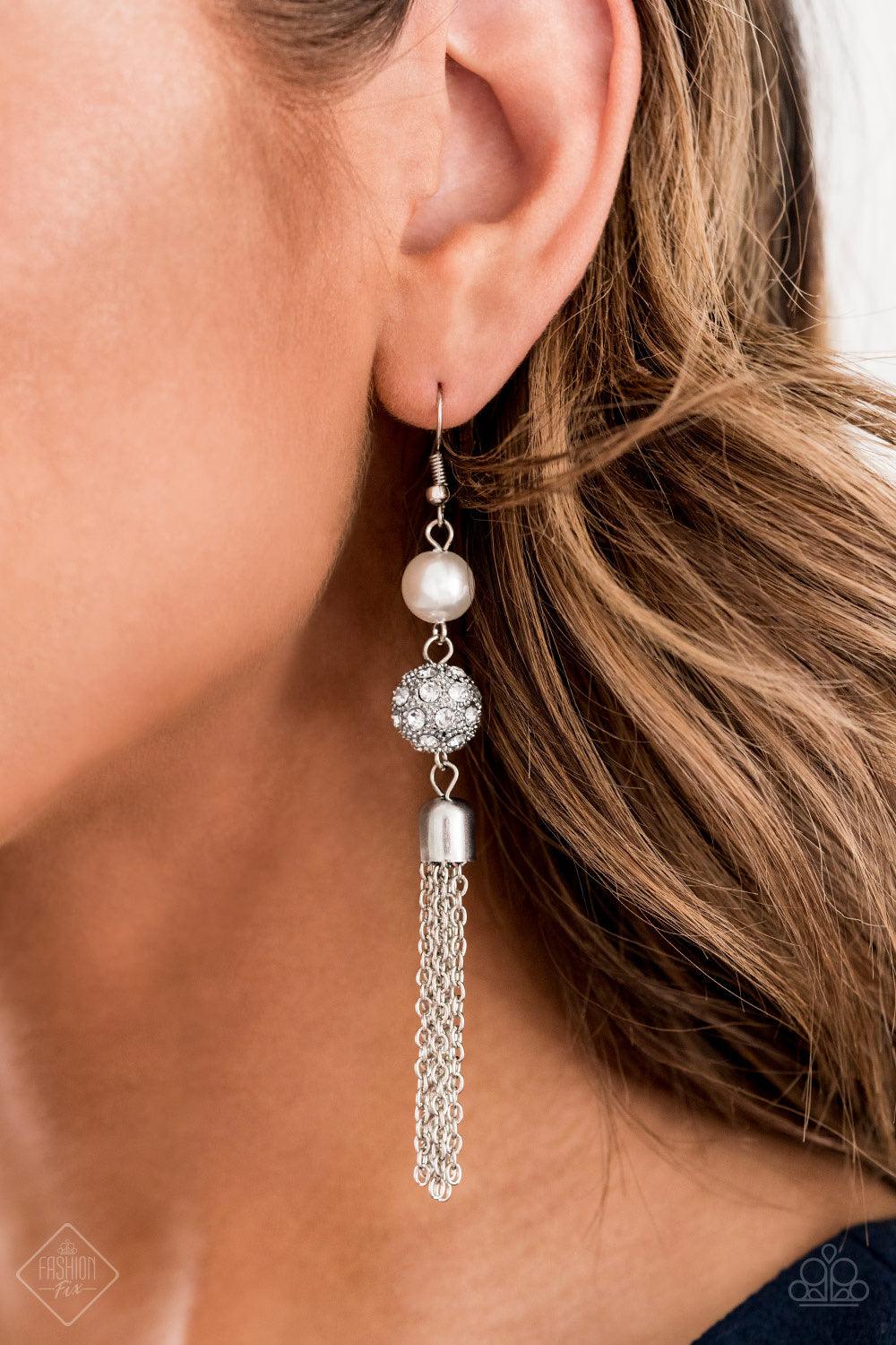 Paparazzi Accessories Going DIOR to DIOR - White A solitaire white pearl gives way to a glittery white rhinestone-encrusted silver bead. A shimmery silver tassel cascades from the bottom of the stacked elegance for a flirty finish. Earring attaches to a s