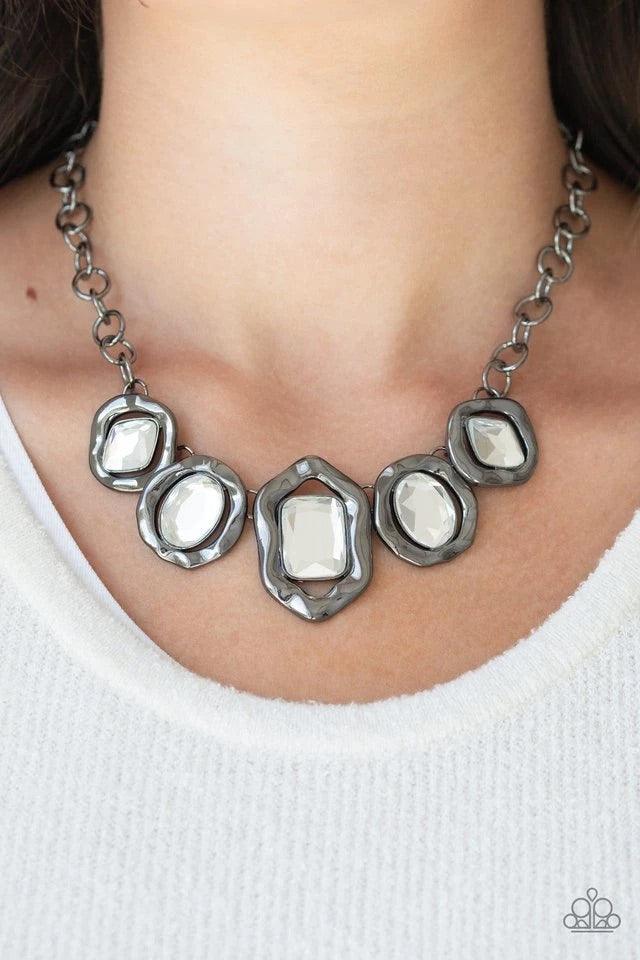 Paparazzi Accessories Celebrity Catwalk - Black Featuring imperfect gunmetal frames, a collection of diamond, oval, and emerald-cut white rhinestones connect below the collar in a blinding fashion. Features an adjustable clasp closure. Sold as one individ