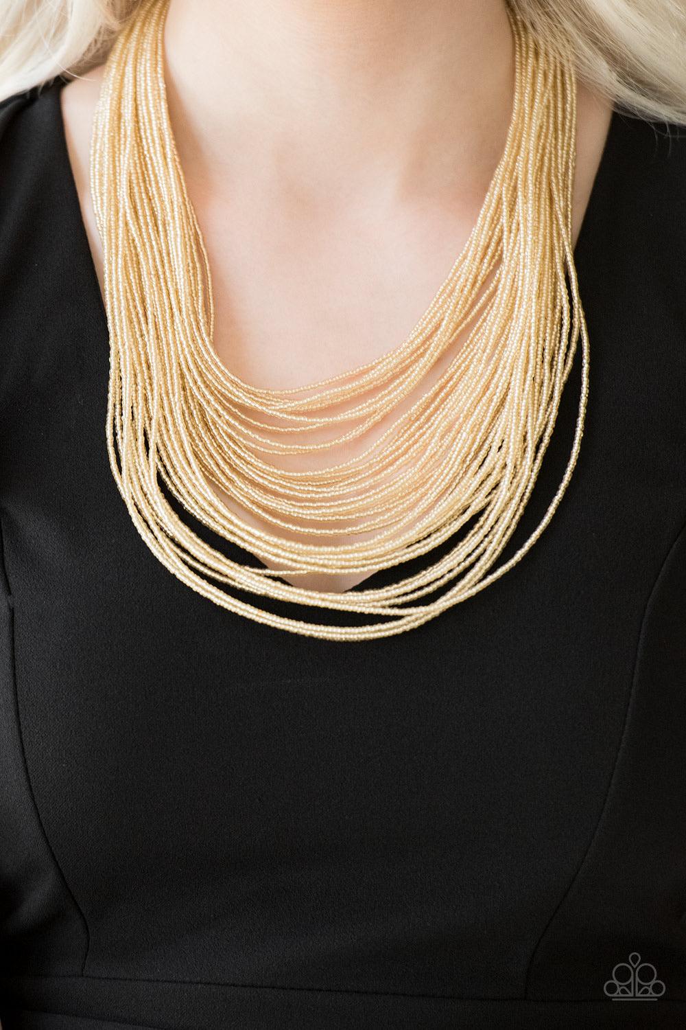Paparazzi Accessories Streaming Starlight - Gold Brushed in a crystal-like shimmer, countless strands of gold seed beads drape across the chest in a bold fashion. Featuring a collision of shapes and shimmer, the glittery strands connect to two large gold