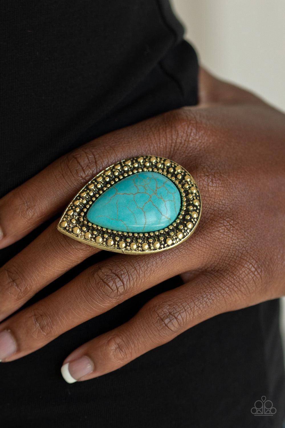 Paparazzi Accessories Santa Fe Storm - Brass Chiseled into a tranquil teardrop, an oversized turquoise stone is pressed into the center of a shimmery brass frame dotted with radiant studded texture for a dramatic stone look. Features a stretchy band for a